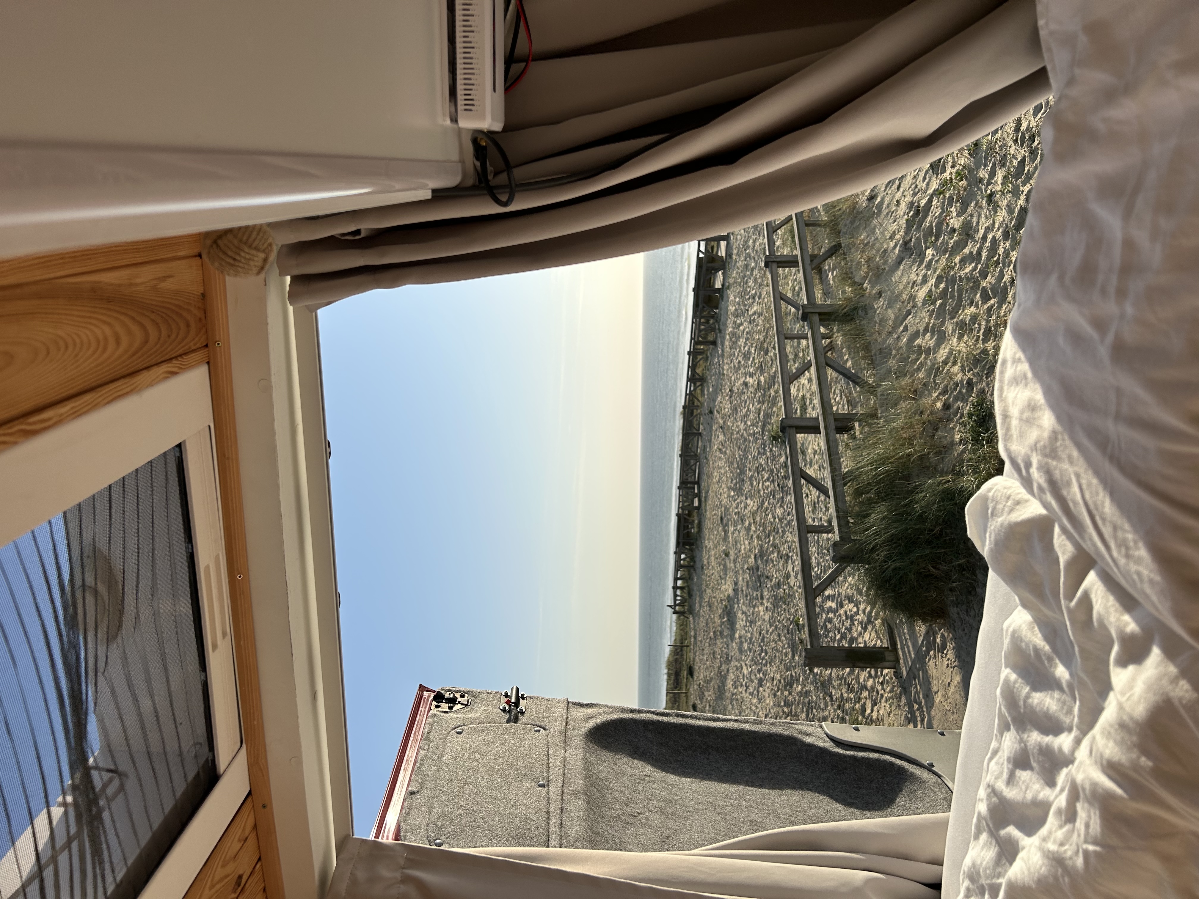 zdjęcie widoku na plaże z otwartych drzwi kampera