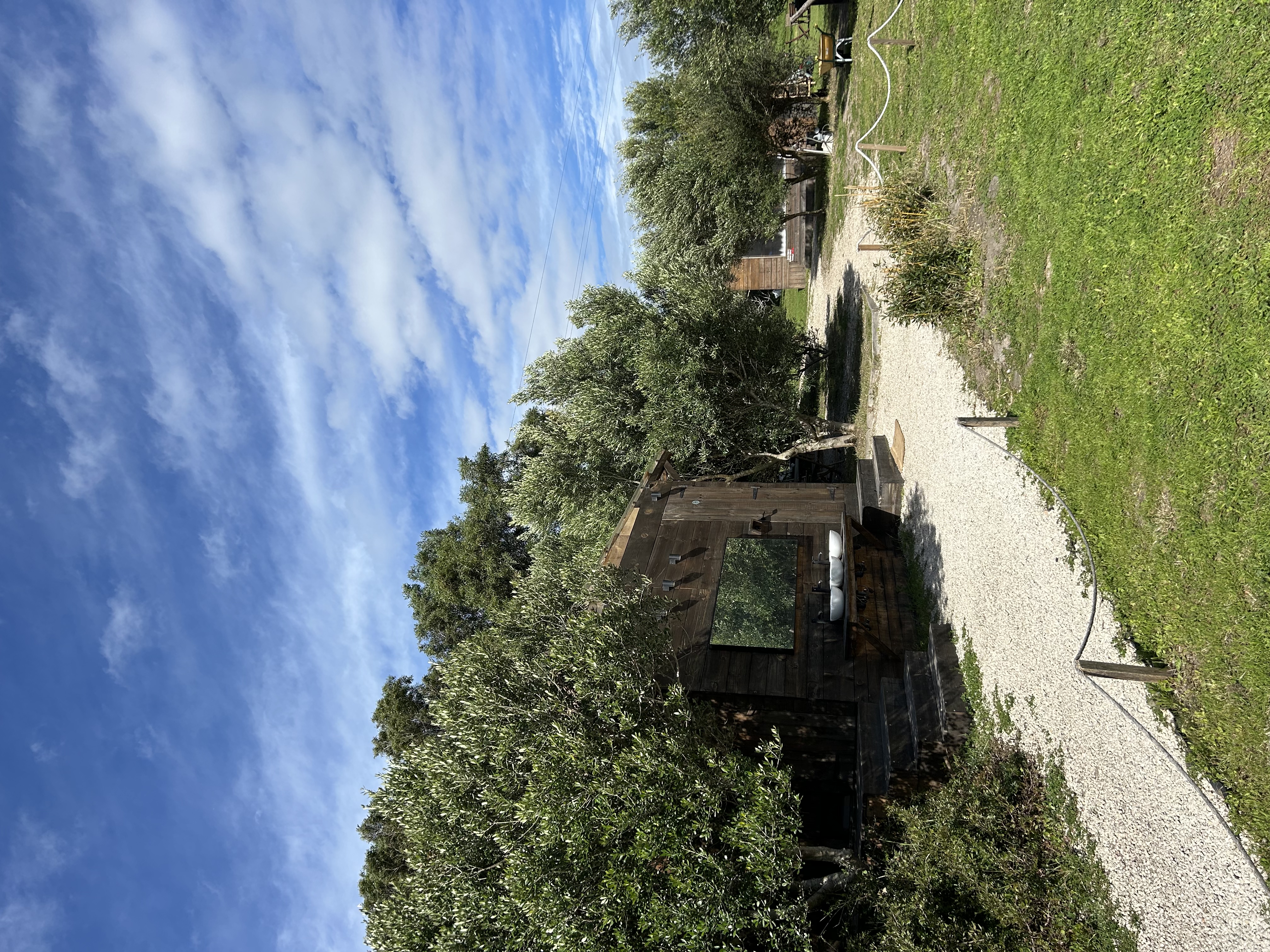 Zdjęcie wejścia do łazienek i dalej w tle osobnego domku z kuchnią.